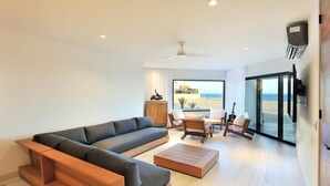 A modern living room with a sectional sofa, a coffee table, and a dining area with chairs. - Oceanfront Terrasol Condo with Patio Fireplace (Cabo San Lucas)