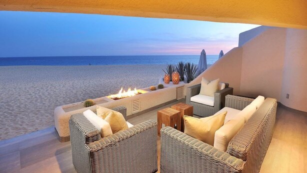 A beachside lounge with wicker furniture, a fire feature, and a view of the sea. - Oceanfront Terrasol Condo with Patio Fireplace (Cabo San Lucas)