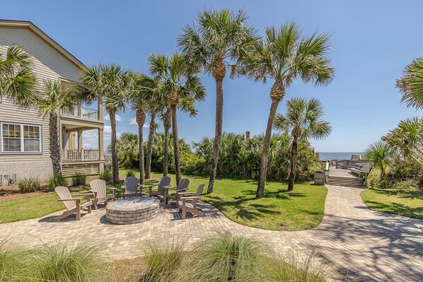 A beachfront property with a patio, outdoor seating, and a fire pit.