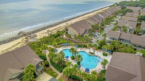 Un resort con piscina rodeada de palmeras, playa y vistas al océano.