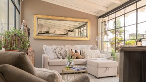 A cozy living room with a beige sofa, a round coffee table, and a large mirror on the wall. - Casa Doper Guadiana (San Miguel de Allende)