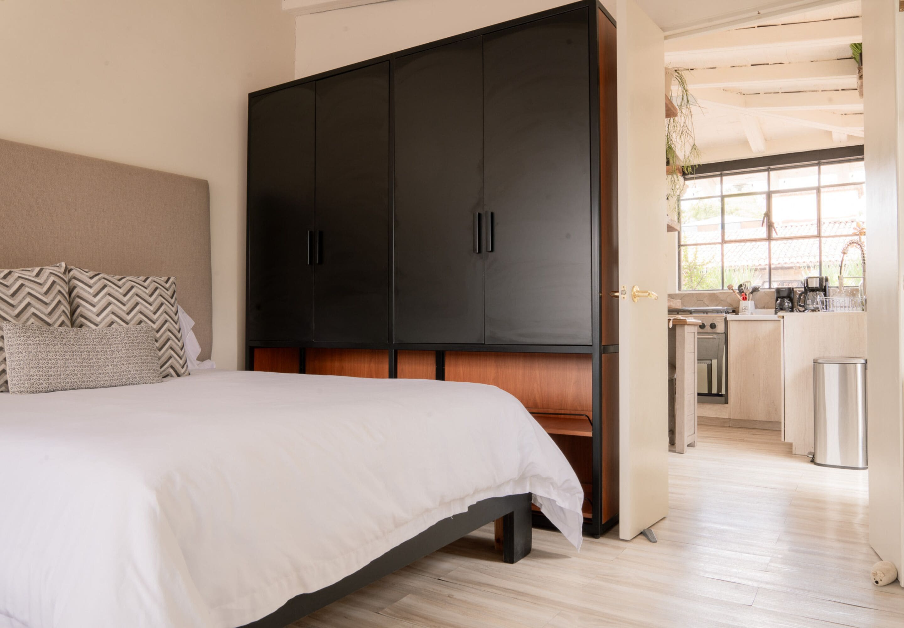 Ein Schlafzimmer mit einem großen Bett, einem Kleiderschrank und Blick auf den Küchenbereich.