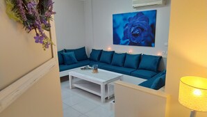 A modern living room with a blue sofa, white coffee table, and a painting of a blue rose. - Modern Quiet Apartment in Rhodes center (Rhodes)