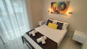 A neatly made bed with white and yellow pillows, a dark headboard, and white nightstands with small drawers. - Modern Quiet Apartment in Rhodes center (Rhodes)