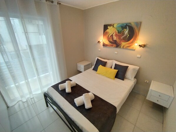 A neatly made bed with white and yellow pillows, a dark headboard, and white nightstands with small drawers. - Modern Quiet Apartment in Rhodes center (Rhodes)