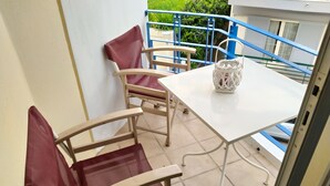 A balcony with two wooden chairs, a white table, and a white lantern. - Modern Quiet Apartment in Rhodes center (Rhodes)