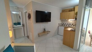 A compact living space with a kitchenette, a flat-screen TV mounted on the wall, and a small dining area. - Modern Quiet Apartment in Rhodes center (Rhodes)