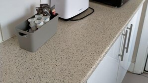 Une cuisine équipée d’un grille-pain, d’un four à micro-ondes et d’une poubelle grise.