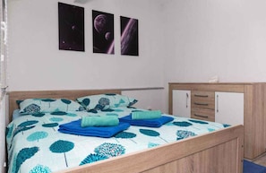 Quarto com cama, duas almofadas, mesa de cabeceira e armário.