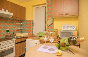 Una cocina con armarios de madera, microondas, estufa y dos copas de vino sobre una mesa.