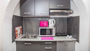 A compact kitchen with a microwave, kettle, and a small sink.