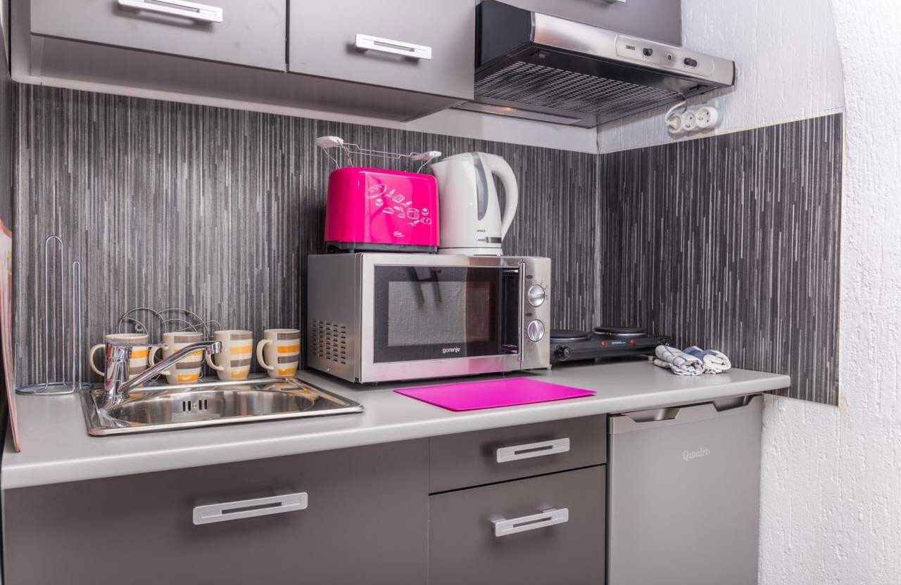 A kitchenette with a microwave, kettle, and coffee maker on the countertop.