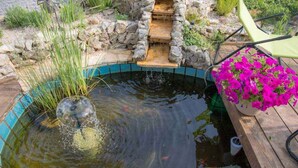 A small pond with a stone border, a water feature, and a chair and potted flowers. - Holiday apartment with terrace and air conditioning (Dramalj)