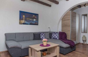 A modern living room with a grey sofa, a wooden coffee table, and a painting of a cityscape.