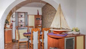 A dining area with a wooden table and chairs, a sailboat model, and a kitchen in the background. - Holiday apartment with terrace and air conditioning (Dramalj)