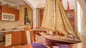 A model ship in a kitchen with wooden cabinets, a microwave, and a window with curtains. - Holiday apartment with terrace and air conditioning (Dramalj)
