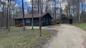 Une cabane avec une allée en gravier, une terrasse en bois et un garage.
