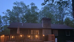 Une cabane avec une véranda, des marches et une cheminée.