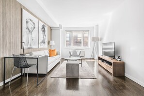 A modern living room with a sofa, a coffee table, a TV, and artwork on the wall.