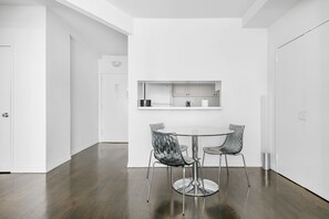 A modern kitchen with white cabinetry, a stainless steel sink, and a round dining table with two chairs.