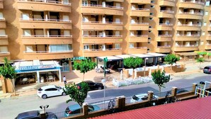 Un edificio residencial de varios pisos con balcones, una cafetería y una farmacia.