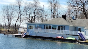 A houseboat with a deck, windows, and a chimney. - Lake Front home with with pontoon boat available for rent (Marcellus)