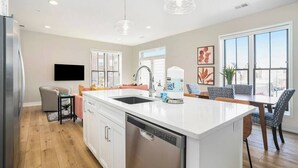 Una cucina moderna con isola centrale, lavastoviglie e zona pranzo con tavolo e sedie.