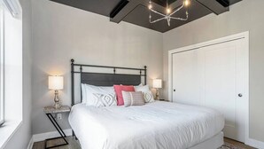 Una camera da letto con un letto grande, due comodini con lampade, un tappeto decorato e una porta bianca.