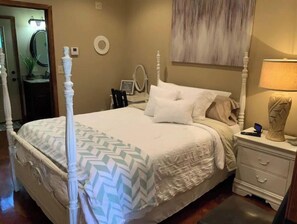Classic four-poster bed with a chevron-patterned bedspread, nightstand, and matching lamp.