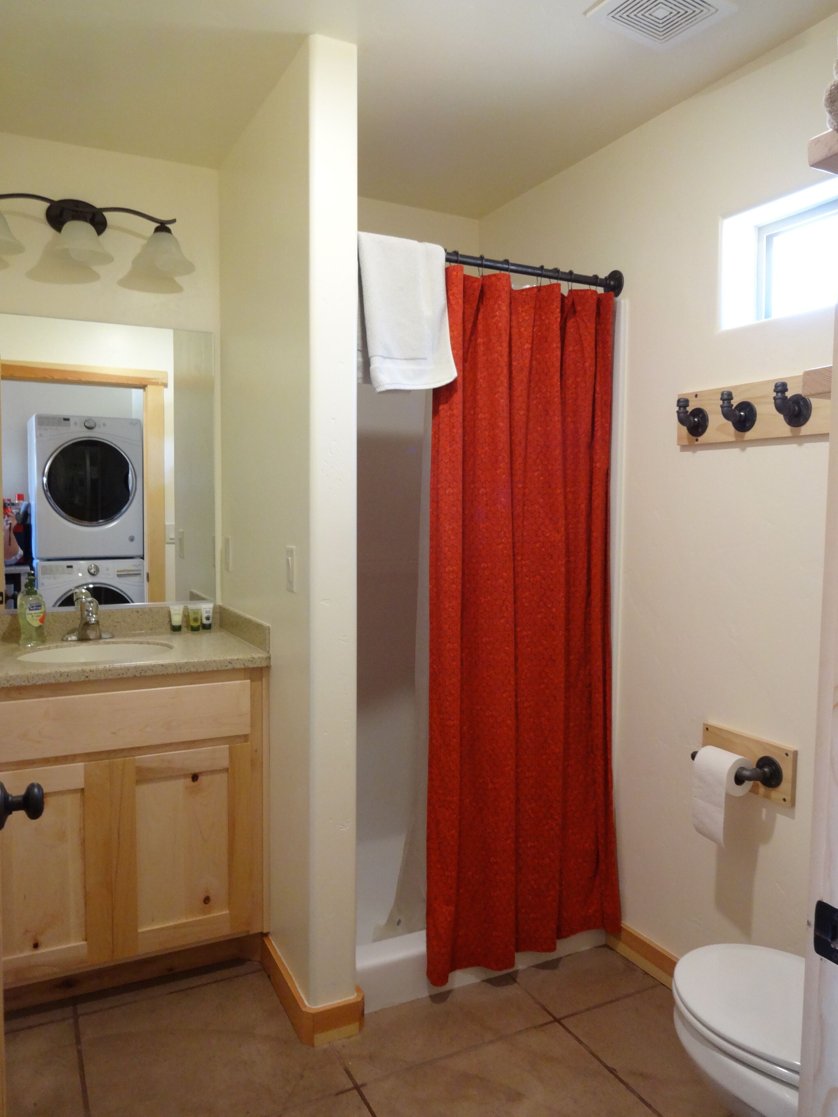 A bathroom with a washing machine, a toilet, and a shower curtain.