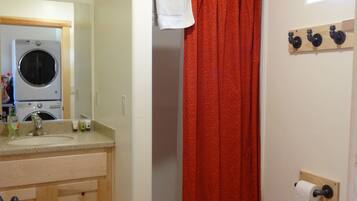A bathroom with a washing machine, a toilet, and a shower curtain.