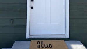 A white front door with a peephole, a mail slot, and a doorbell. There is a doormat with "OH HELLO" written on it. - Cozy BV Home w/ views: 1mi to Main St STR-111 (Buena Vista)