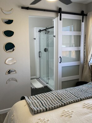Une chambre avec un lit, une cabine de douche en verre et une armoire à porte coulissante.