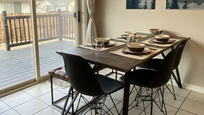 A dining area with a table set for four, a sliding glass door leading to a deck, and two landscape paintings on the wall. - Cozy BV Home w/ views: 1mi to Main St STR-111 (Buena Vista)