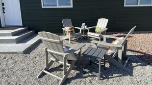 An outdoor seating area with Adirondack chairs and a small table, set against a dark green building with white-framed windows. - Cozy BV Home w/ views: 1mi to Main St STR-111 (Buena Vista)