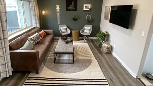 A living room with a brown sofa, two armchairs, a coffee table, and a TV on the wall. - Cozy BV Home w/ views: 1mi to Main St STR-111 (Buena Vista)