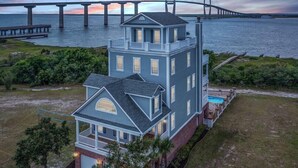 A two-story house with a balcony and a swimming pool, located near a large bridge over water. - ☀️Picturesque Views💥Game room👙Pool & Hot Tub (Brunswick)