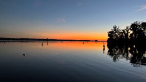 Un lago tranquilo al atardecer, con cielo despejado y árboles reflejándose en el agua.