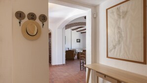 A hallway with a rustic brick floor, a wooden bench, and a wall-mounted hat rack with numbered hooks. - BIG HOUSE with BBQ and dining room outside (Tossa de Mar)