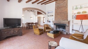 A living room with a fireplace, wooden furniture, and a television. - BIG HOUSE with BBQ and dining room outside (Tossa de Mar)