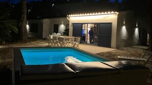 A swimming pool with lounge chairs and a table, surrounded by a building with a covered patio area. - BIG HOUSE with BBQ and dining room outside (Tossa de Mar)