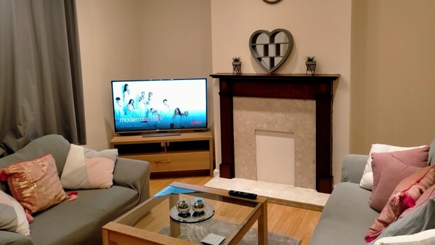 Una sala de estar con televisión, sofá, mesa de centro y chimenea.