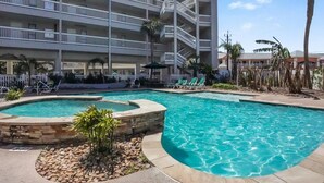 A hotel with a pool area, multiple balconies, and palm trees. - Beachfront Breeze! Front Row/Heated Pool/Unobstructed Ocean Views!  (Galveston)