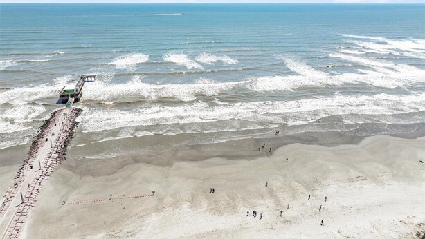 A beach with a long pier extending into the ocean, a sandy shore, and a clear sky. - Beachfront Breeze! Front Row/Heated Pool/Unobstructed Ocean Views!  (Galveston)