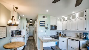 A kitchen with white cabinets, a granite countertop, a microwave, and a coffee maker. - Beachfront Breeze! Front Row/Heated Pool/Unobstructed Ocean Views!  (Galveston)