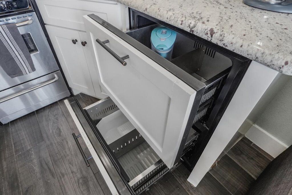 A kitchen with a stainless steel oven, a built-in dishwasher, and a granite countertop.