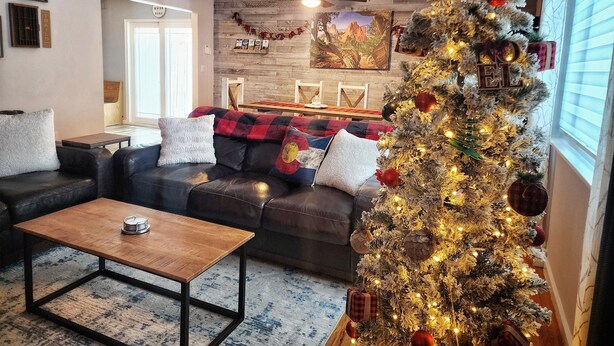 A cozy living room with a leather sofa, a wooden coffee table, and a decorated Christmas tree.