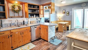 A kitchen with wooden cabinets, a dishwasher, and a dining area with a bench.