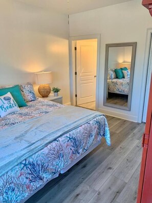 Une chambre à coucher avec un lit, une table de chevet, une lampe, une plante en pot et un miroir.