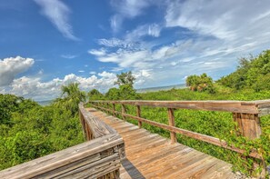 A wooden boardwalk leading through a lush green landscape with a clear sky above.